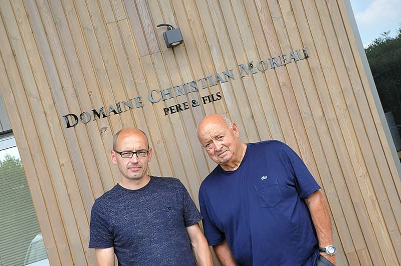 Fabien et Christian Moreau devant la façade de bois de la cuverie du domaine